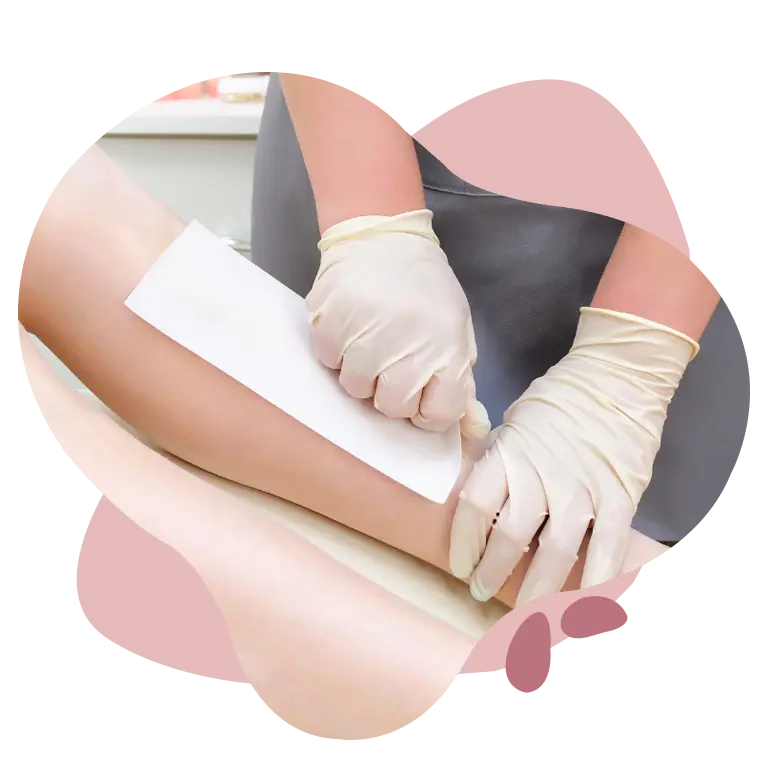 Close-up of a beautician wearing gloves applying a waxing strip on a client’s leg for hair removal in a professional salon setting.