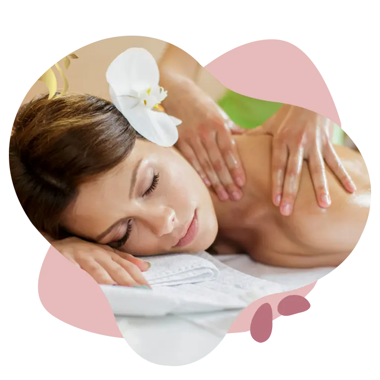 Woman receiving a relaxing back massage in a spa setting, lying on a towel with a white orchid in her hair.